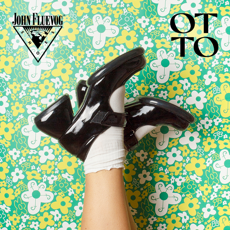 A pair of black John Fluevog Sol Shoes set up against a green, yellow and white floral wallpaper. The wallpaper is part of an exclusive collaboration between John Fluevog and Otto Studio.