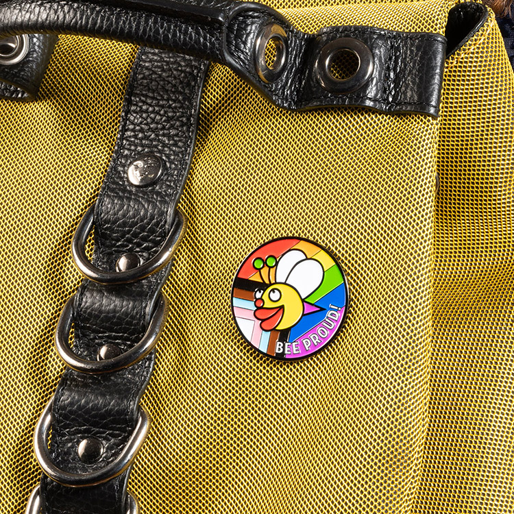 The 2024 Fluevog Pride Pin attached to a yellow backpack.