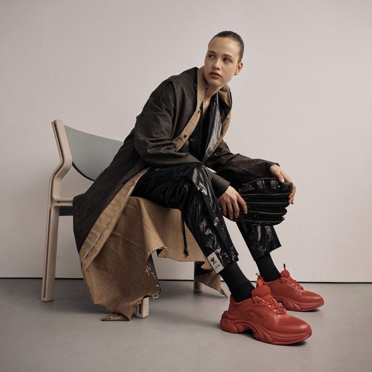 Cake Magazine: Model Tess wears the red Soul Speed Duesy sneakers and a long overcoat while sitting in a chair.